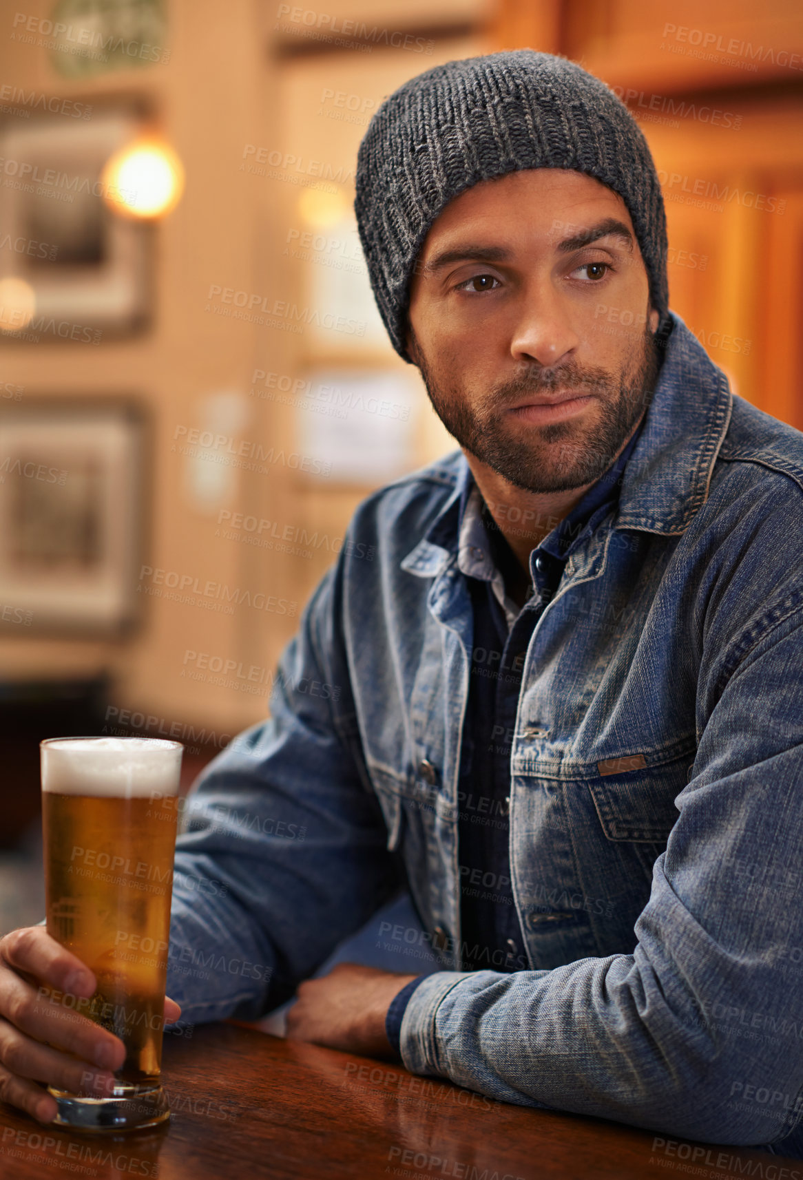 Buy stock photo Beer, thinking and male person at pub for drinks, restaurant and entertainment for fun. Pensive, alcohol and cafe for thoughtful or social for relax, pub and beanie for cold weather in England  