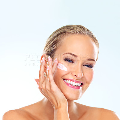 Buy stock photo Woman, smile and portrait with cream on face for skincare, dermatology, and self care in studio. Female person, happy and cosmetic product with lotion, sunscreen or beauty glow on blue background