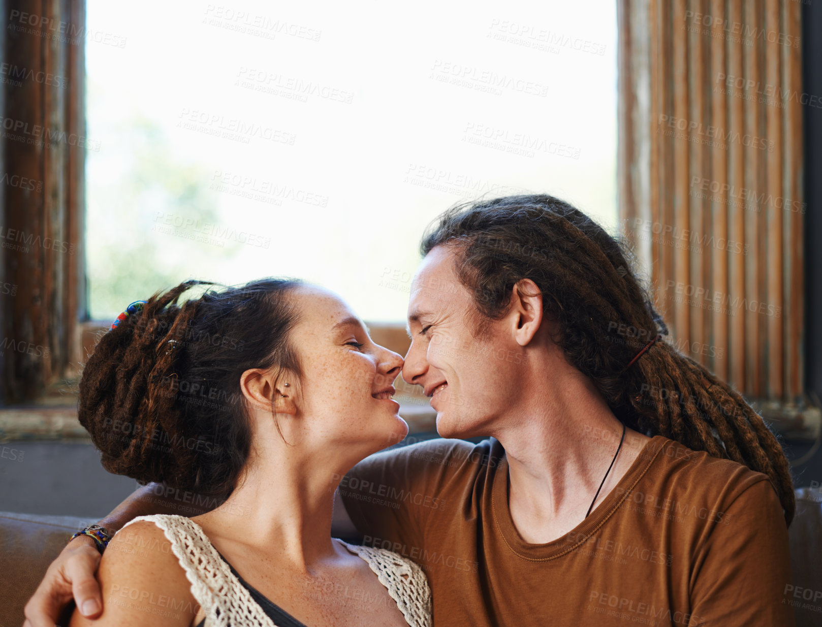 Buy stock photo Shot of an affectionate dread-locked couple sitting at home