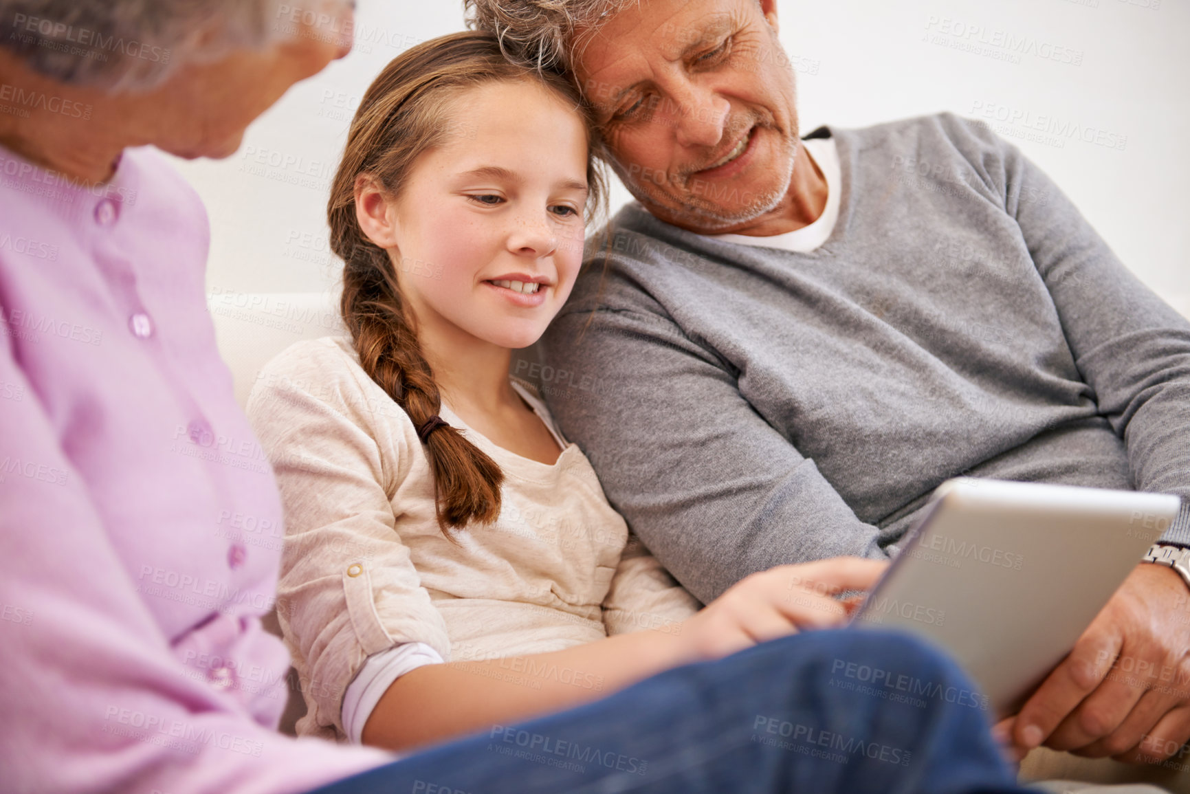Buy stock photo Shot of grandparents watching their granddaughter use a digital tablet