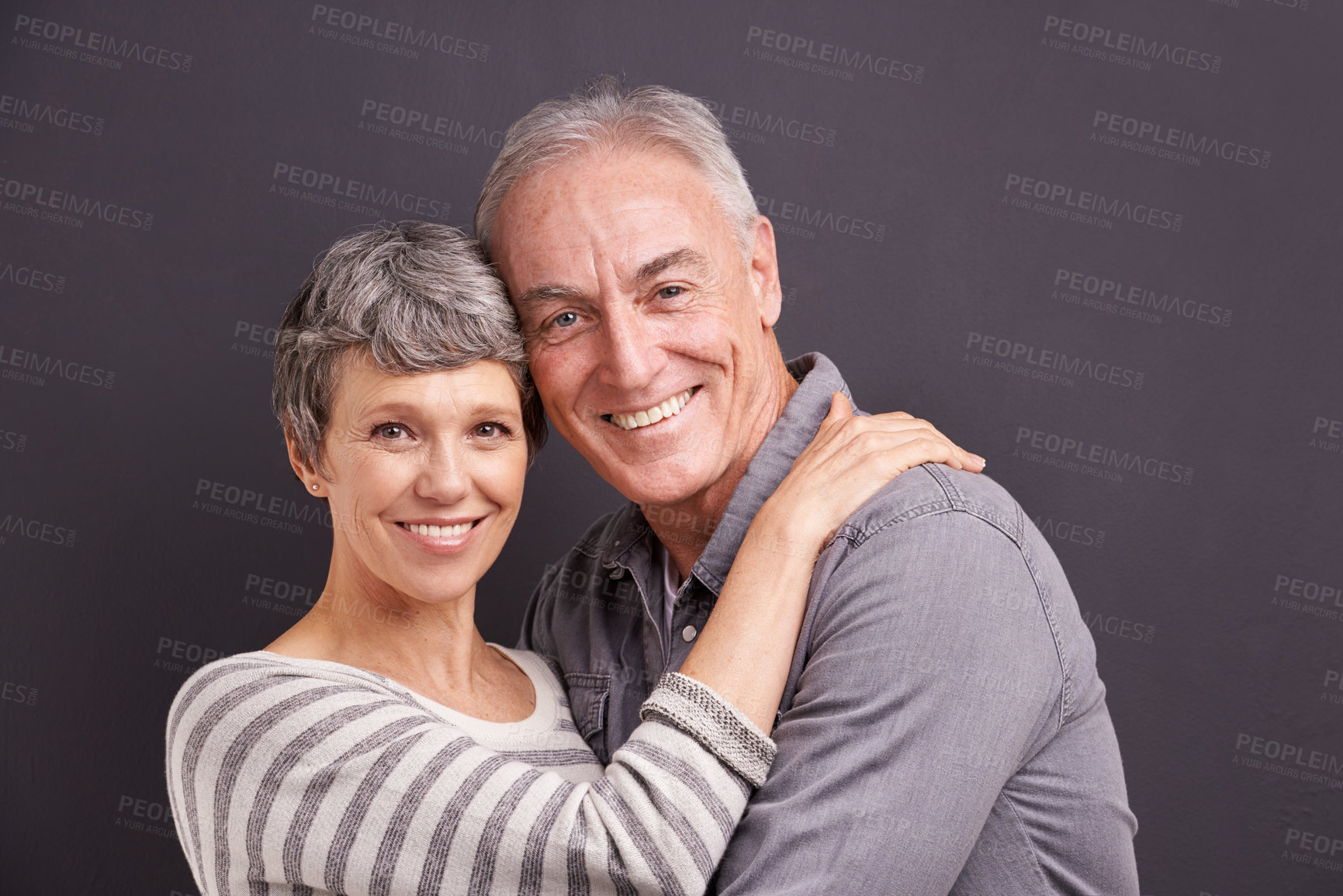 Buy stock photo Portrait, hug and senior couple with love, retirement and romance on grey studio background. Anniversary, face and old man with mature woman or embrace with relationship, marriage or bonding together