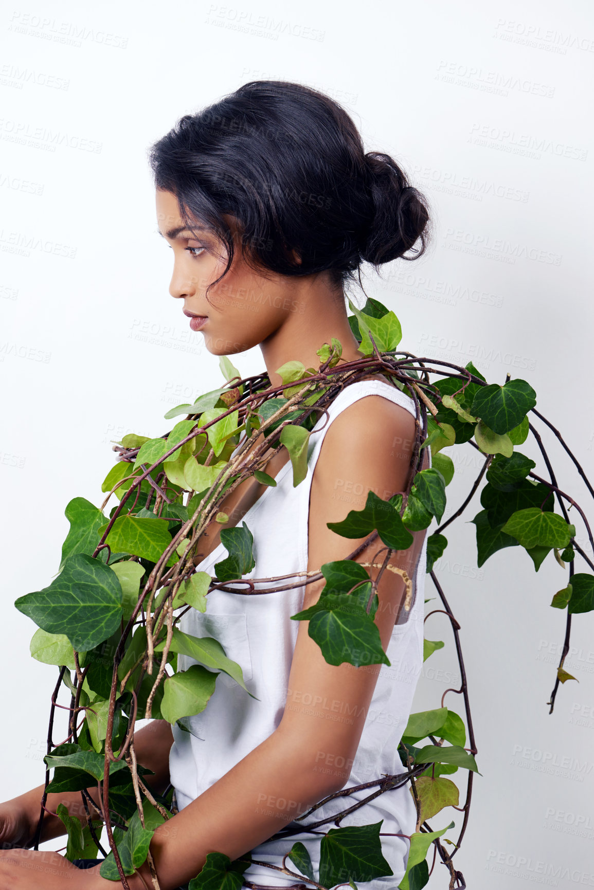 Buy stock photo Studio shot of an attractive young ethnic woman with foliage over her shoulder