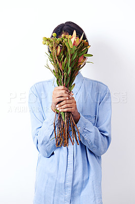 Buy stock photo Woman, bouquet and cover face in studio with leaves, fashion and sustainability by white background. Person, model and mystery with flowers, plants and organic clothes with ecology for environment