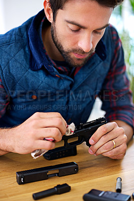 Buy stock photo A young man cleaning his gun