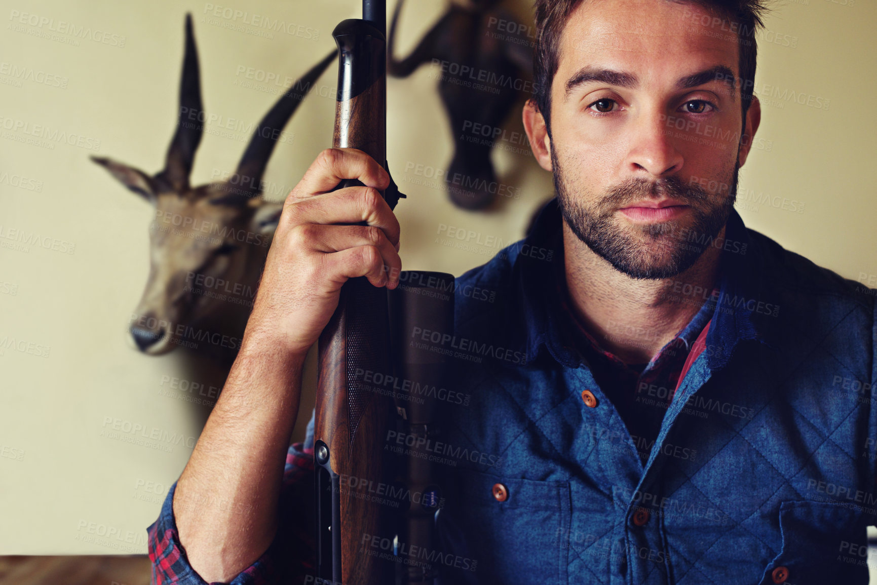 Buy stock photo Hunting, trophy and portrait of man with gun for game shooting, adventure and hobby with confidence. Sports hunter and serious person in cabin with rifle, pride and animal head collection in home
