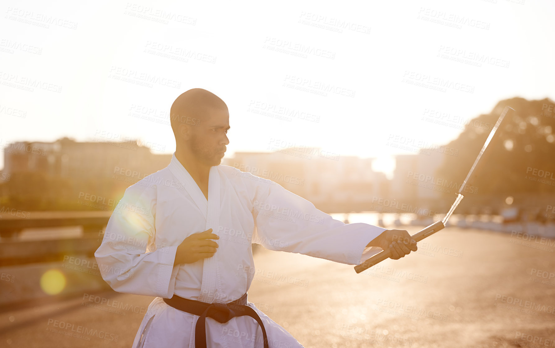 Buy stock photo Man, karate and fitness with nunchuck in city for fighting style, technique or combat skill. Young male person or taekwondo fighter with weapon in martial arts or self defense on street in urban town