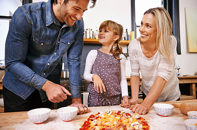 Buy stock photo Parents, girl and cooking pizza in kitchen with cheese, learning and helping hand for development in home. Father, mother and daughter with dough, teaching and support with bonding in family house