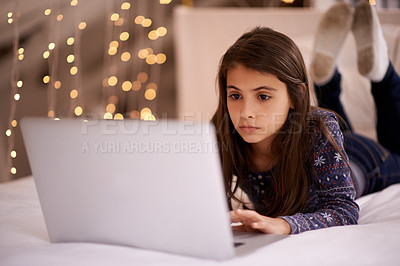 Buy stock photo Cropped shot of a cute little girl using her laptop while lying on her bed