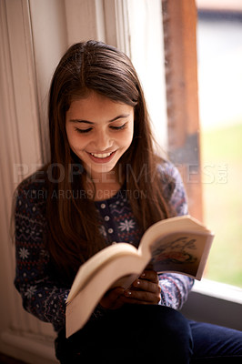 Buy stock photo Girl, kid and book with smile in home for reading, learning and language by window for studying. Child, literacy and thinking with story, happy and fantasy with education in family house in Madrid