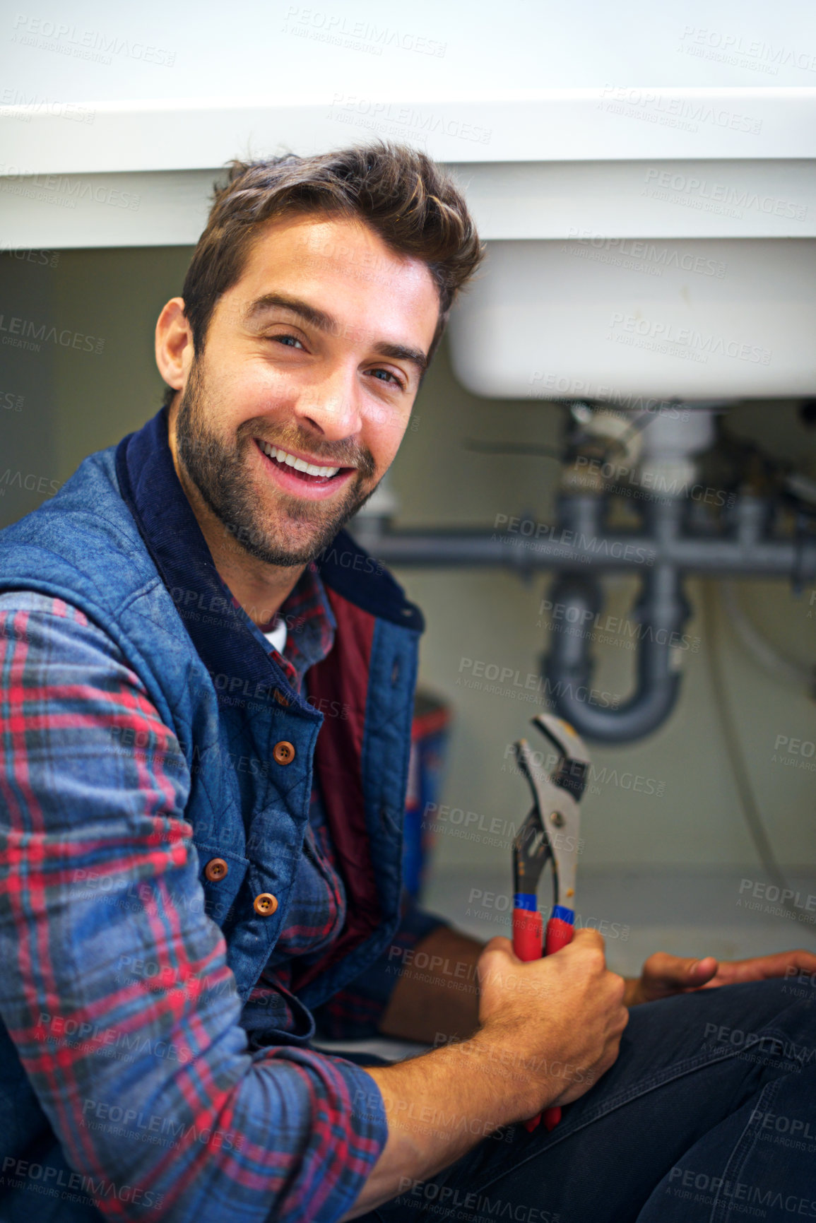 Buy stock photo Shot of a plumber fixing a pipe
