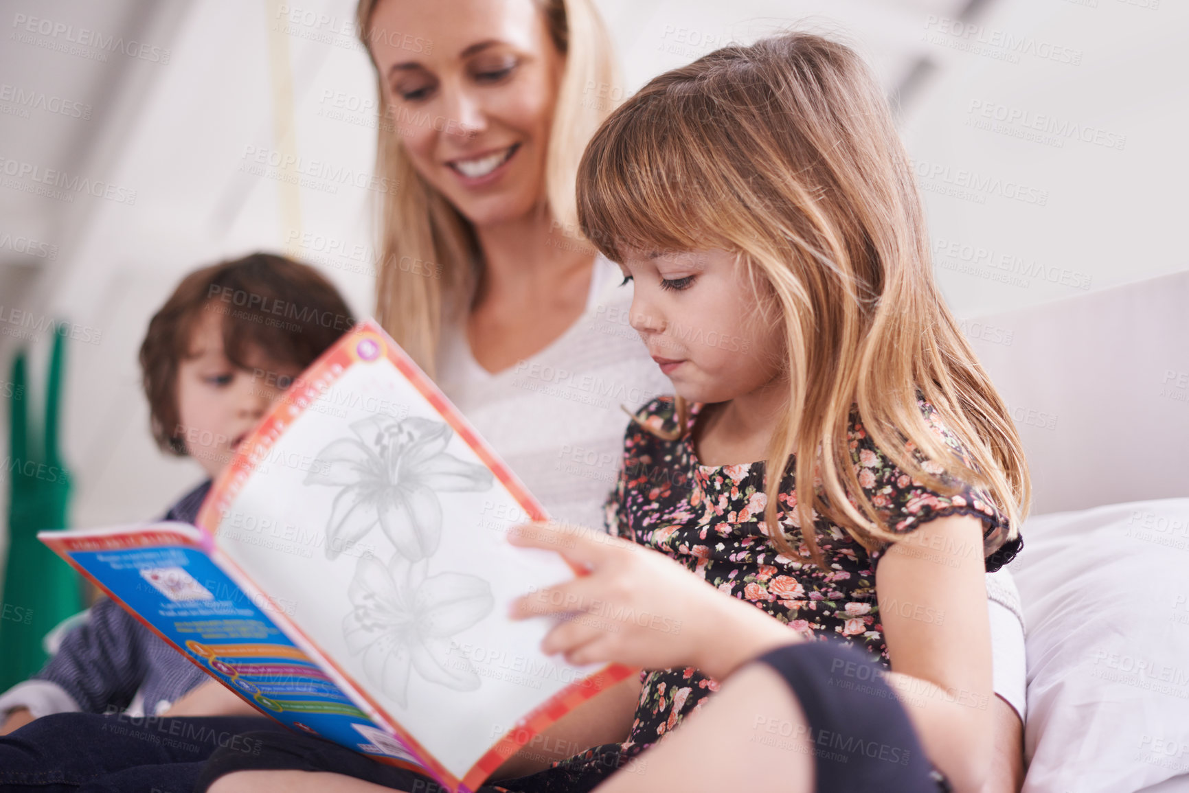 Buy stock photo Shot of a mother reading with her children at home