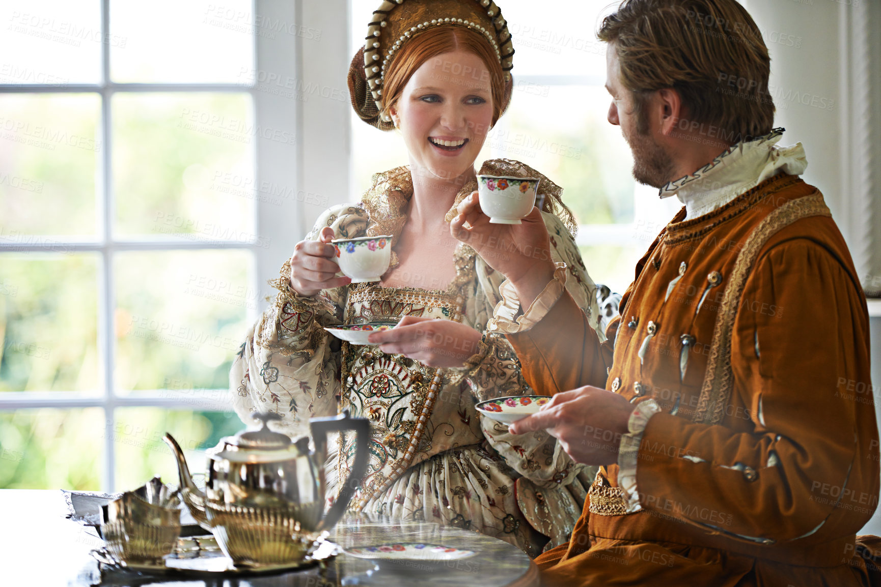 Buy stock photo King, queen and couple with tea at castle, smile and conversation in vintage clothes for royalty at breakfast. Woman, man and drink together in morning with Victorian fashion at regal palace in UK