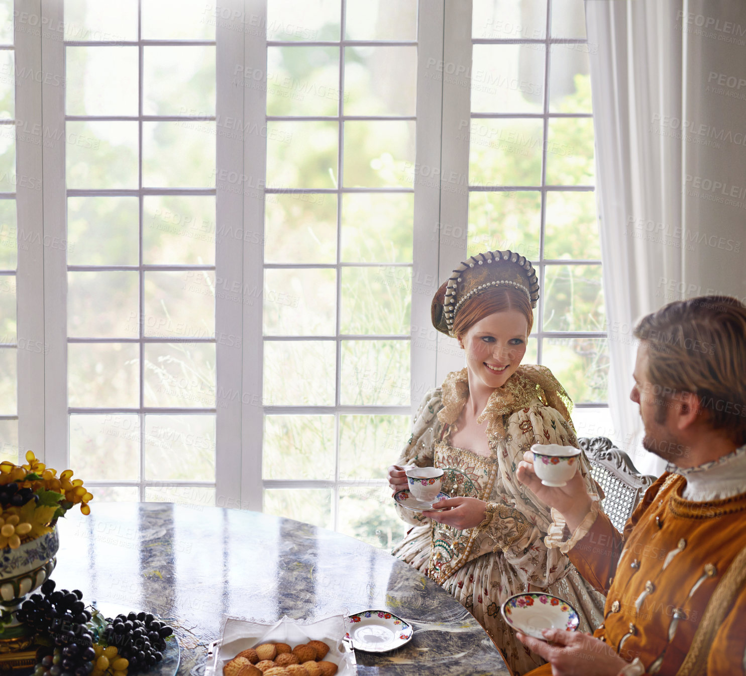 Buy stock photo King, queen and couple with tea in costume, smile and conversation in vintage clothes in castle at breakfast. Woman, man and drink together in morning with Victorian fashion at regal palace in UK