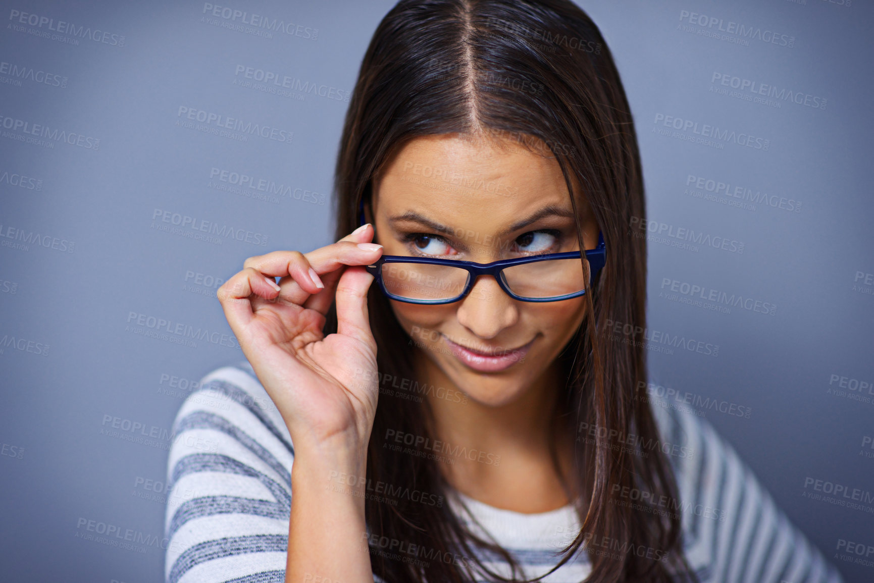 Buy stock photo Woman, glasses and looking in studio for suspicion, relax and playful on blue background. Female person, mockup space and smile for eyewear satisfaction, confidence and enjoyment for spectacle pride