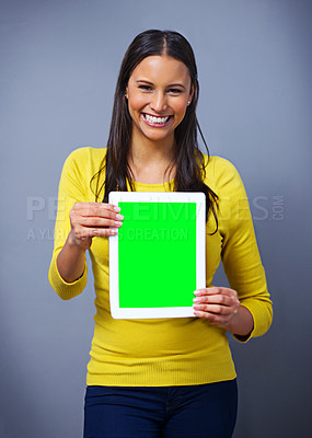 Buy stock photo Studio portrait of an attractive young woman holding a tablet against a blue background