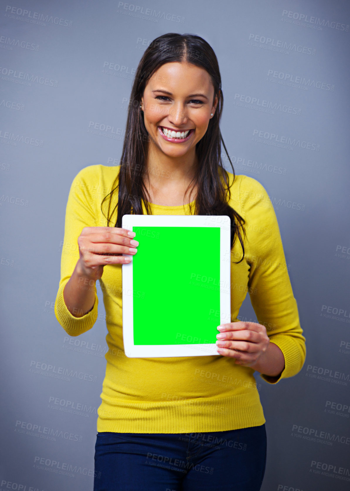 Buy stock photo Studio portrait of an attractive young woman holding a tablet against a blue background