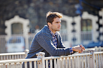 Buy stock photo Shot of a handsome young man leaning over a railing