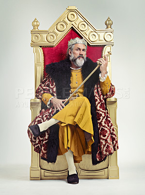 Buy stock photo Studio shot of a richly garbed king sitting on a throne holding his scepter