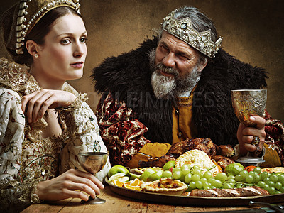 Buy stock photo King, queen and talk with feast at table for fine dinning in royal banquet, vintage and majestic with crown. Monarch, husband and bored together with alcohol for buffet for formal celebration.