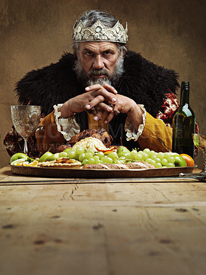 Buy stock photo King, food and portrait in banquet hall on table for feast with wine and fruit for eat and drink. Mature person or man with crown for royalty and stern facial expression for power, rank and buffet   