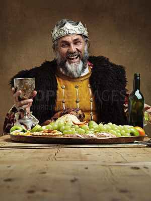 Buy stock photo King, feast and happy in table with wine glass as lord on dining hall for tradition, culture and meal in palace. Portrait, monarch and leader with eating buffet or supper in royal party with crown 