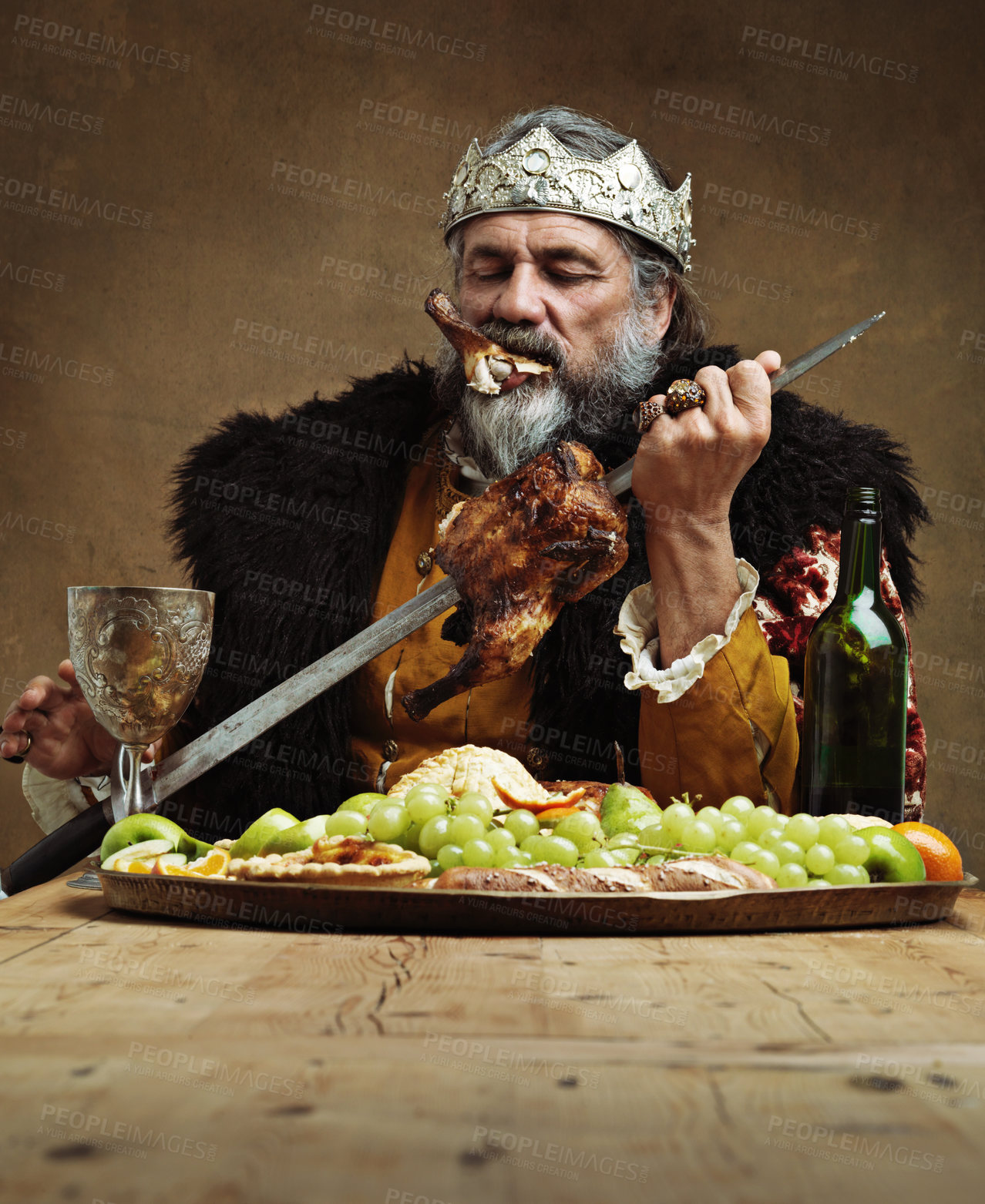 Buy stock photo King, man and food at table with wine as royalty on dining hall for tradition, culture and meal in palace. Monarch, leader and eating buffet or supper with sword for chicken with fruit and luxury