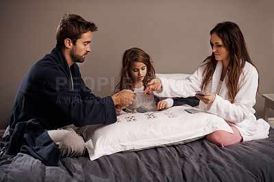 Buy stock photo Parents, girl and fun while playing cards in home for bonding, learning and relax with strategy in bedroom. Father, mother and daughter with games, maths and teaching with connection in family house
