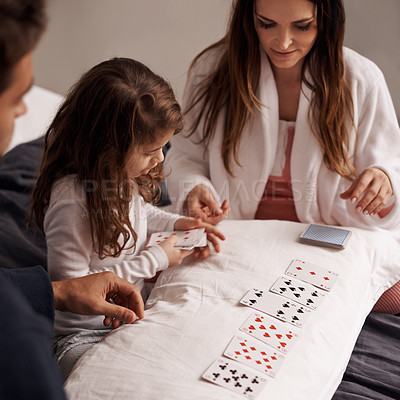 Buy stock photo Mom, father and girl with playing cards for game with bonding, learning and relax with strategy in bedroom. Dad, mother and daughter with deal, deck and child on bed with connection in family house