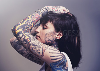 Buy stock photo Tattoo, edgy design and rebel with woman, punk rock and tradition on a grey studio background. Profile, person and model with ideas or creative with emo and gothic art with ink, trendy or heavy metal