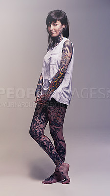 Buy stock photo Studio shot of a young woman covered in tattooes