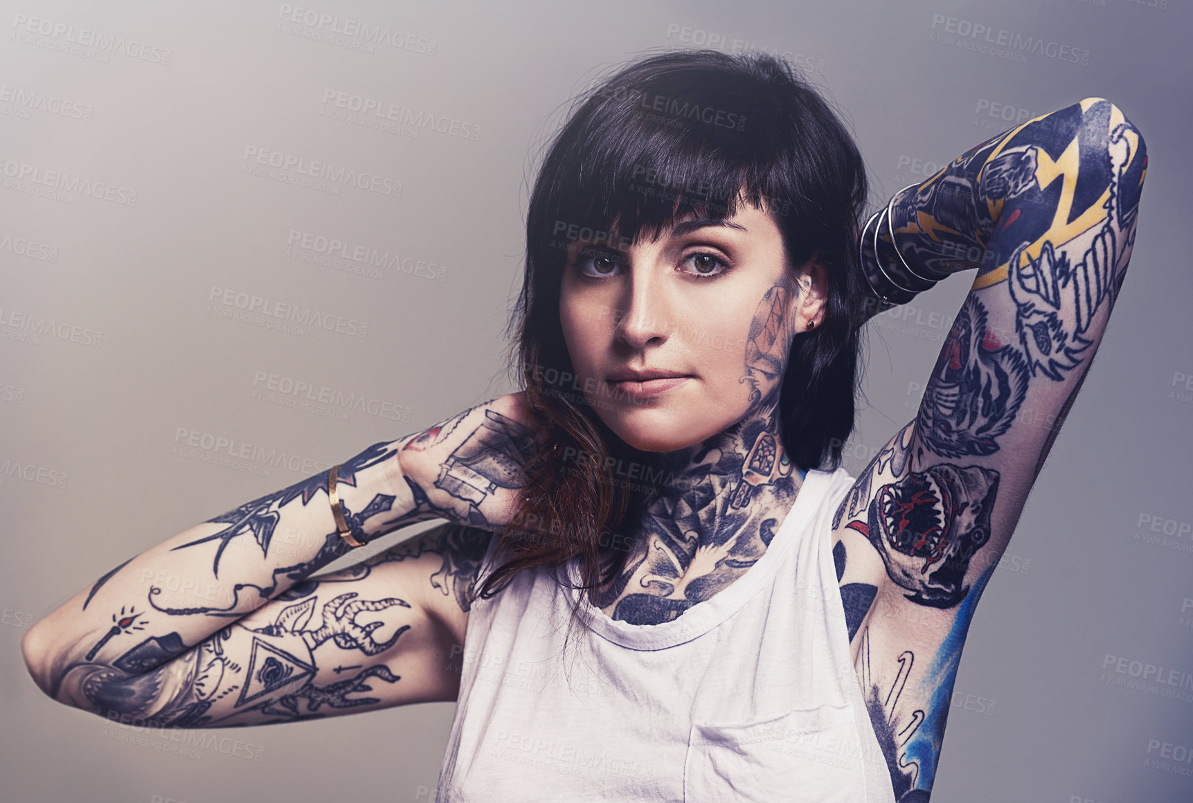 Buy stock photo Portrait, tattoo and edgy with a woman in a tank top on a studio gray background for contemporary style. Fashion, body art and punk with an attractive young female model posing to show her ink