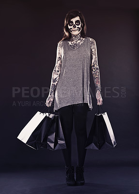 Buy stock photo Woman, skull makeup and shopping bags in studio on dark background with retail and discount for halloween. Portrait, female person and tattoo with edgy or creative style, body art and confidence