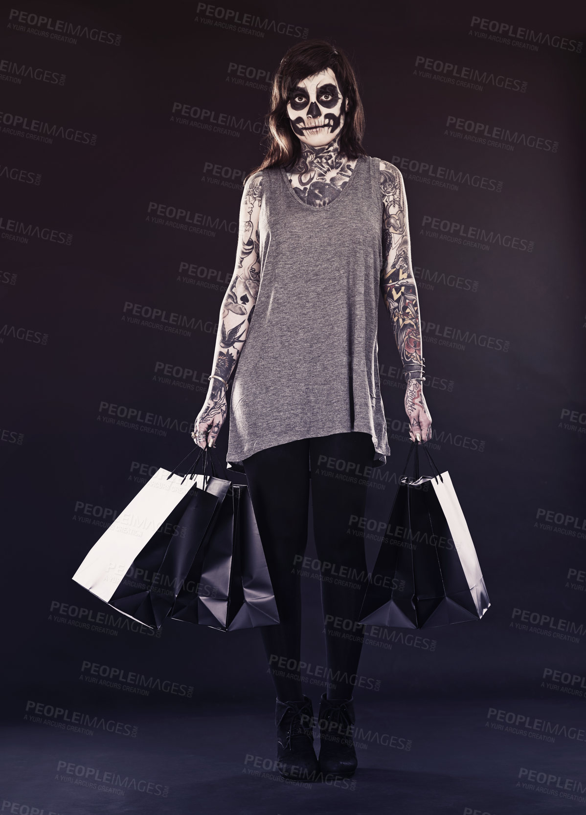 Buy stock photo Woman, skull makeup and shopping bags in studio on dark background with retail and discount for halloween. Portrait, female person and tattoo with edgy or creative style, body art and confidence