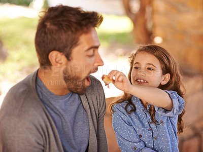 Buy stock photo Dad, girl and feeding in park for breakfast and wellness, family, picnic and love. Man, child and bonding with food and together for fathers day, people or kids and smile, health or joy and happiness