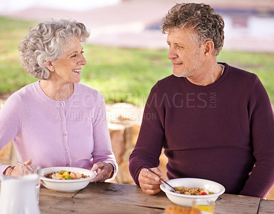 Buy stock photo Outdoor, senior and couple with smile for breakfast, eating and happiness in backyard for romance. Partners, woman and man in marriage with food in nature of garden in home, fruit and nutrition