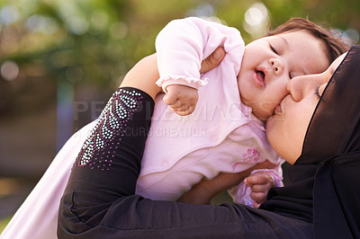 Buy stock photo Muslim mother, outdoor and kiss baby for care, connection and bonding together in summer. Mom, kid and love on cheek for infant, adorable child and Islamic family at garden for healthy relationship