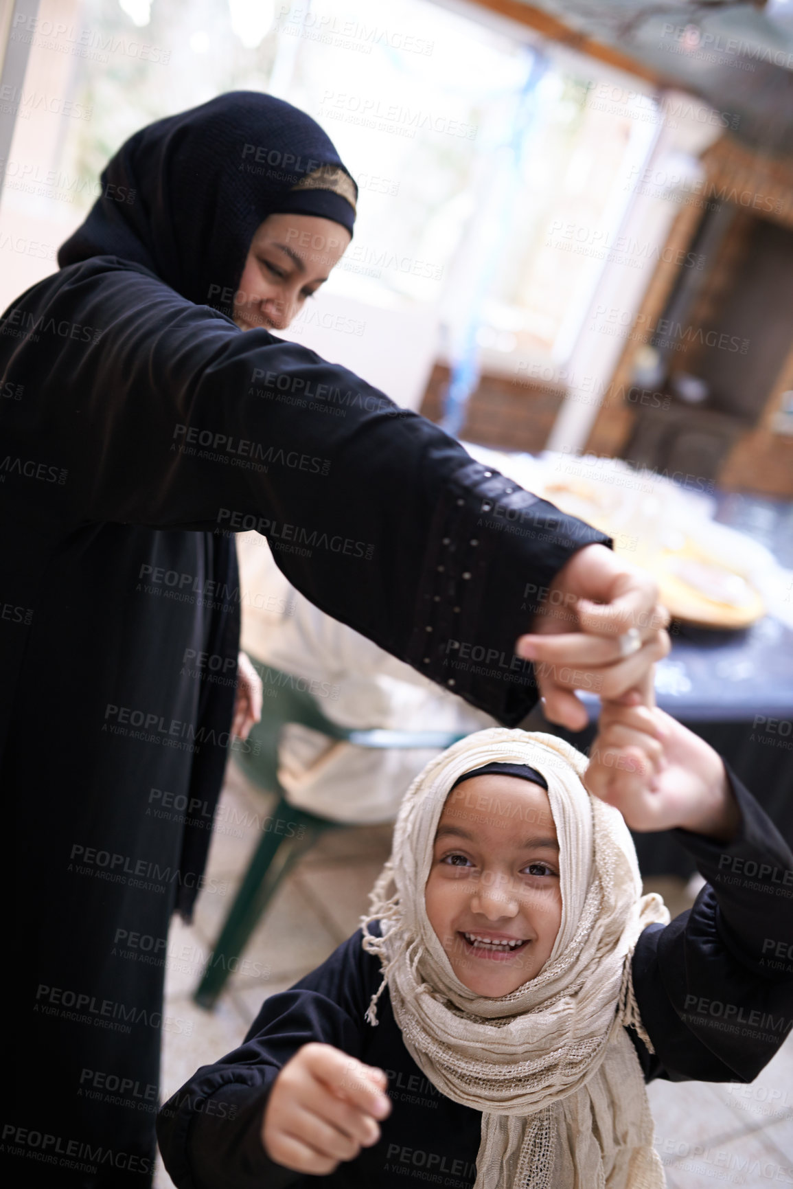 Buy stock photo Muslim, mom and child in home playing a game and dance in living room with happiness in Islamic family. Excited, girl and mother in house together holding hands with energy in spinning movement