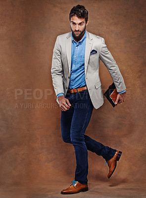 Buy stock photo Business, fashion and man walking with book in studio for travel, commute or work routine on brown background. Corporate, trip or male entrepreneur with style, confidence or outfit choice for journey