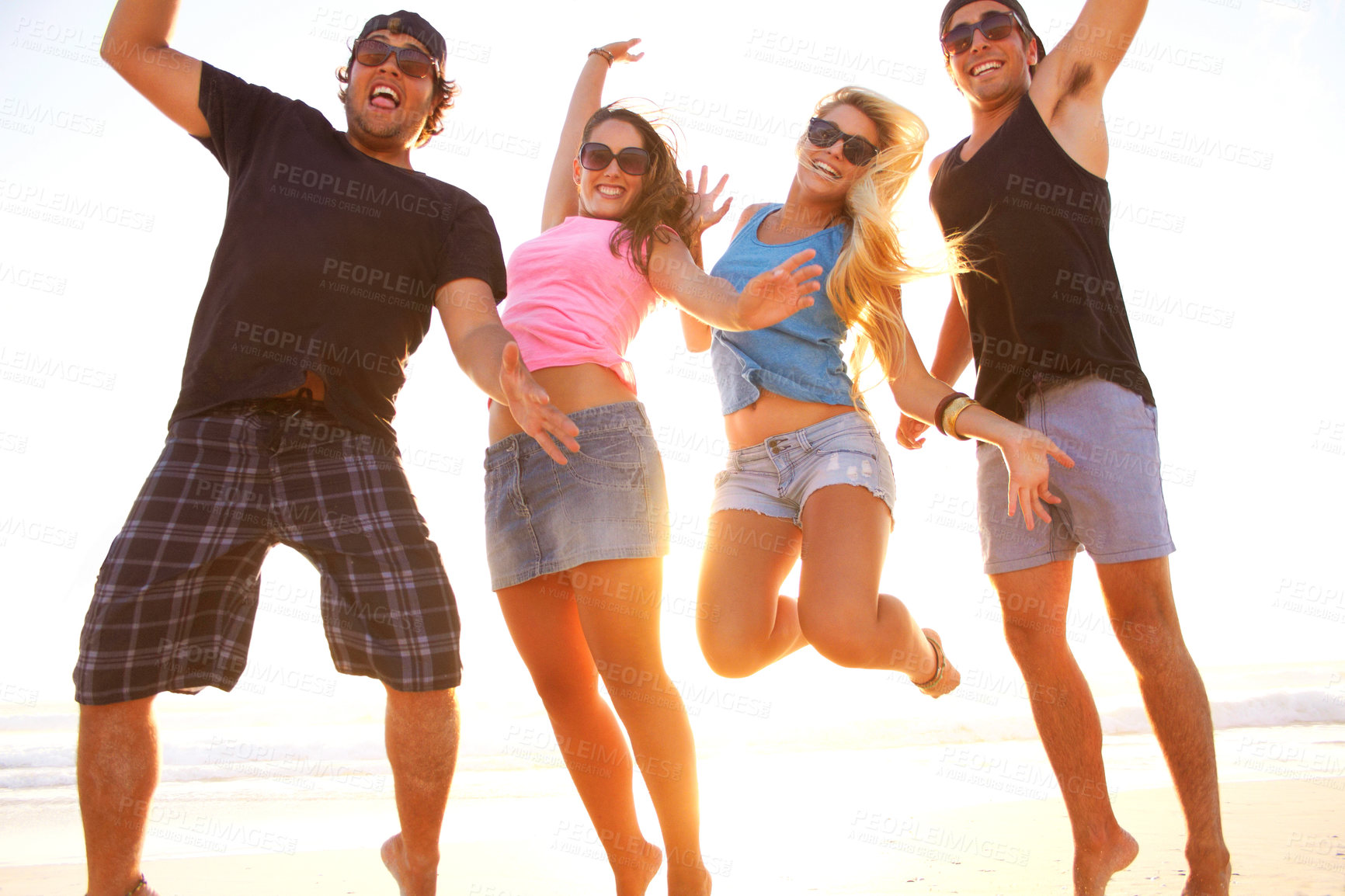 Buy stock photo Shot of a group of friends walking along a beach at sunset