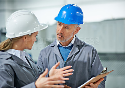 Buy stock photo Two factory employees wearing hardhats having a discussion