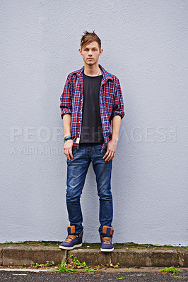 Buy stock photo Man, student and relax on wall in city, trendy clothes and style in urban town. Male person, portrait and outdoor with confidence on street with fashion, generation z and streetwear at university