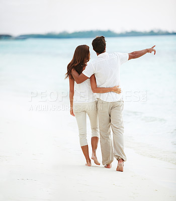Buy stock photo Rear-view of an affectionate young couple pointing to the ocean while on a romantic stroll