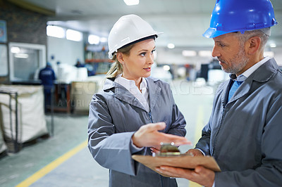 Buy stock photo Man, woman and conversation with clipboard in warehouse for quality inspection or safety checks and process monitoring. Team, communication and board for manufacturing information in printing factory