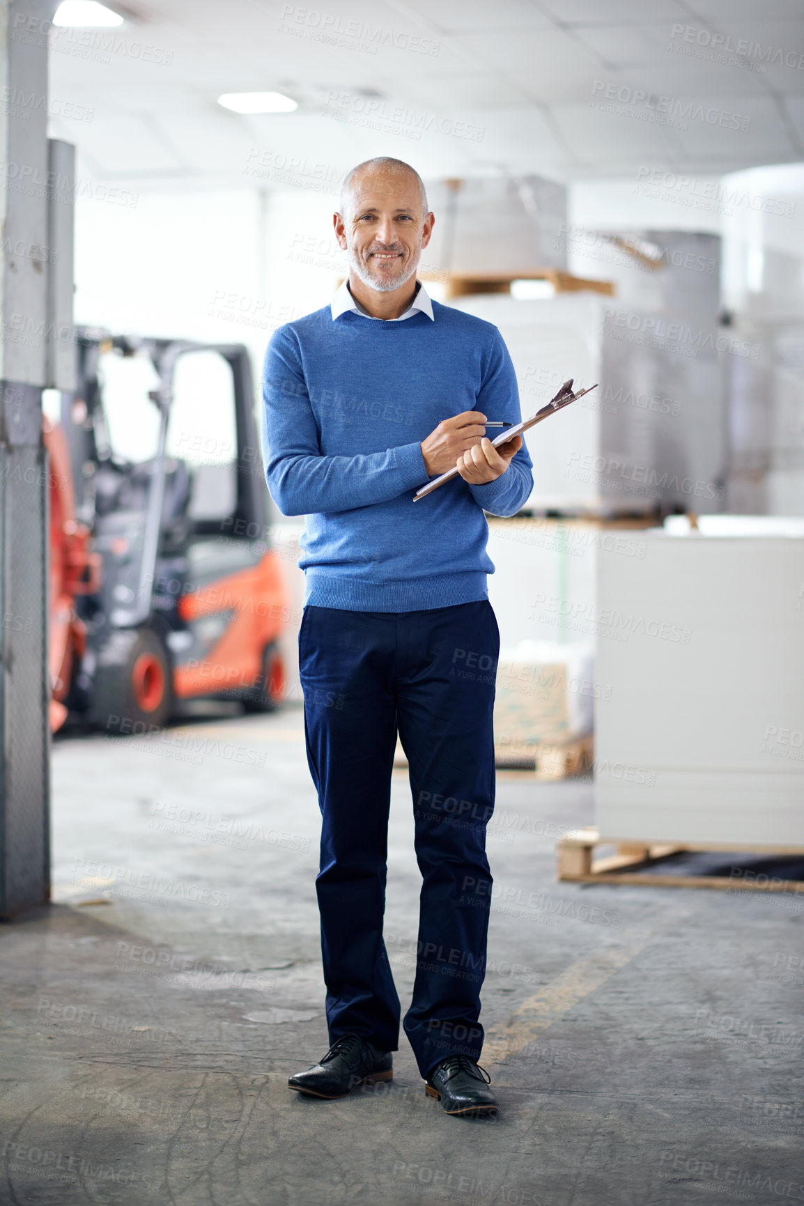 Buy stock photo A manager standing on the factory floor with a clipboard and a smile