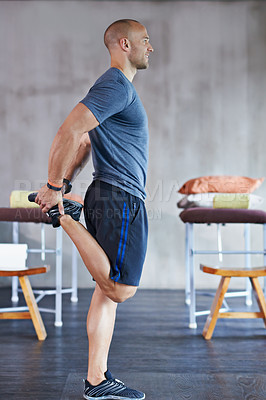 Buy stock photo A cropped shot of a handsome trainer stretching before a workout session