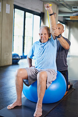 Buy stock photo Physiotherapist, helping and senior man with elastic, training and elderly support for care. Men, gym and exercise for health, wellness and coaching with yoga ball for mature rehab and wellbeing