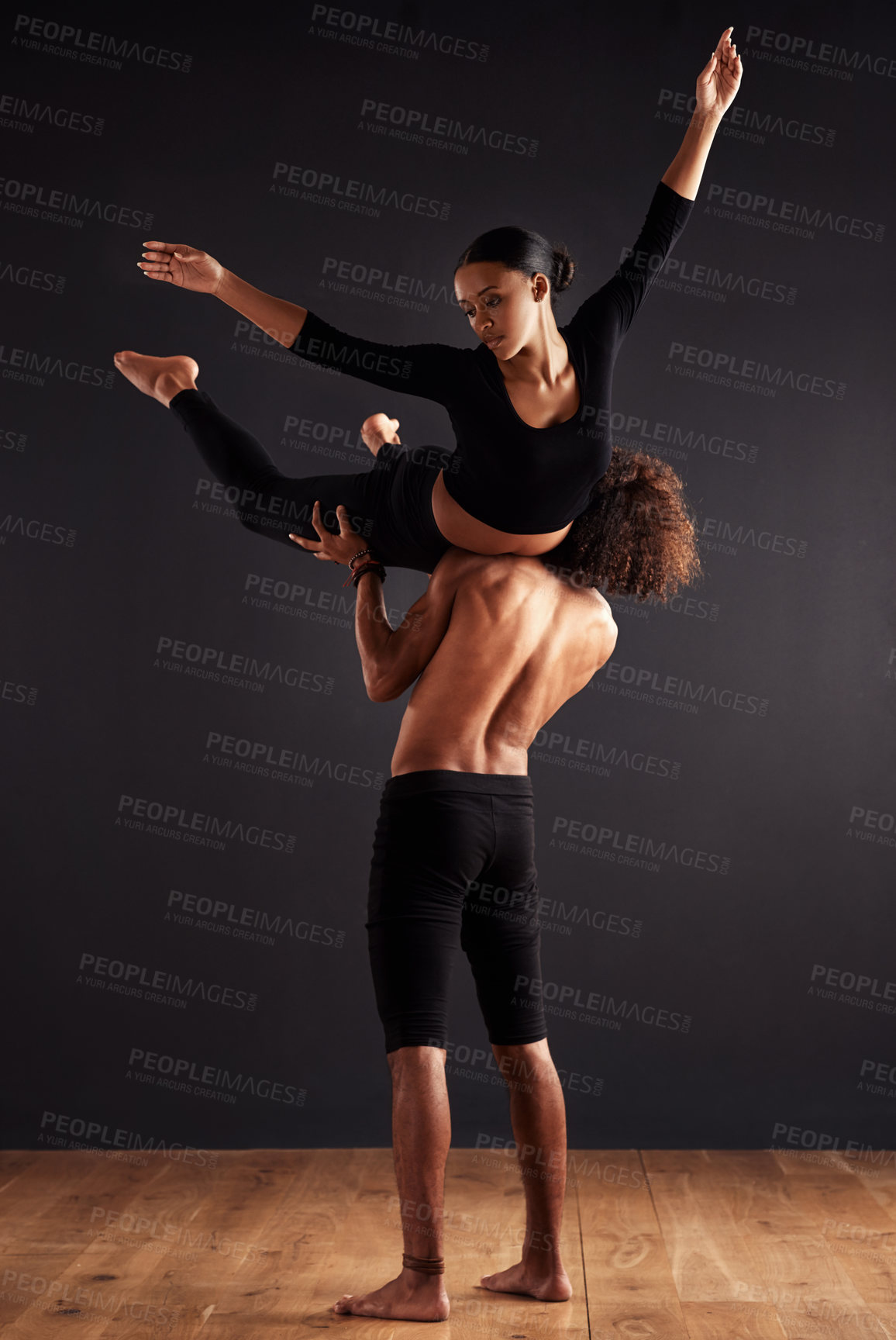 Buy stock photo A female and male contemporary dancer performing a dramatic pose in front of a dark background