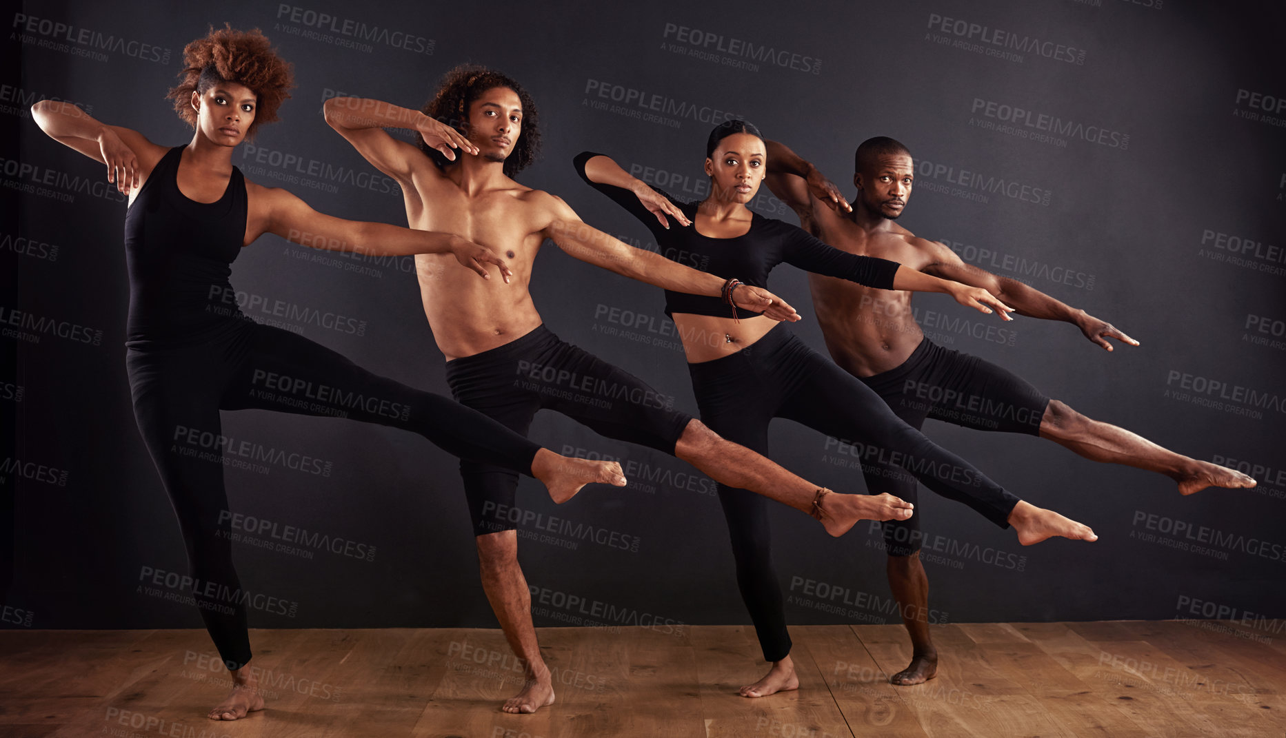 Buy stock photo A group of dancers performing a dramatic pose in front of a dark background