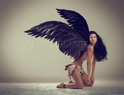 Buy stock photo Shot of a woman with wings kneeling against gray background