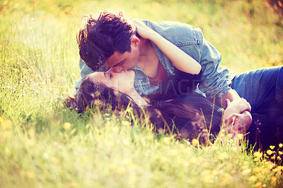 Buy stock photo Love, kiss and relax with couple in grass field for summer, date and valentines day bonding. Affectionate, romance and nature with man and woman lying in garden meadow for spring, youth and happy